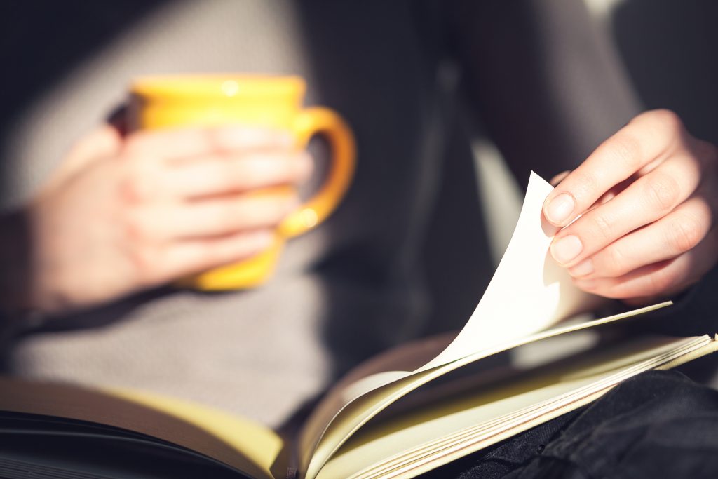 Close-up of woman hands holding open book. Woman reading book.