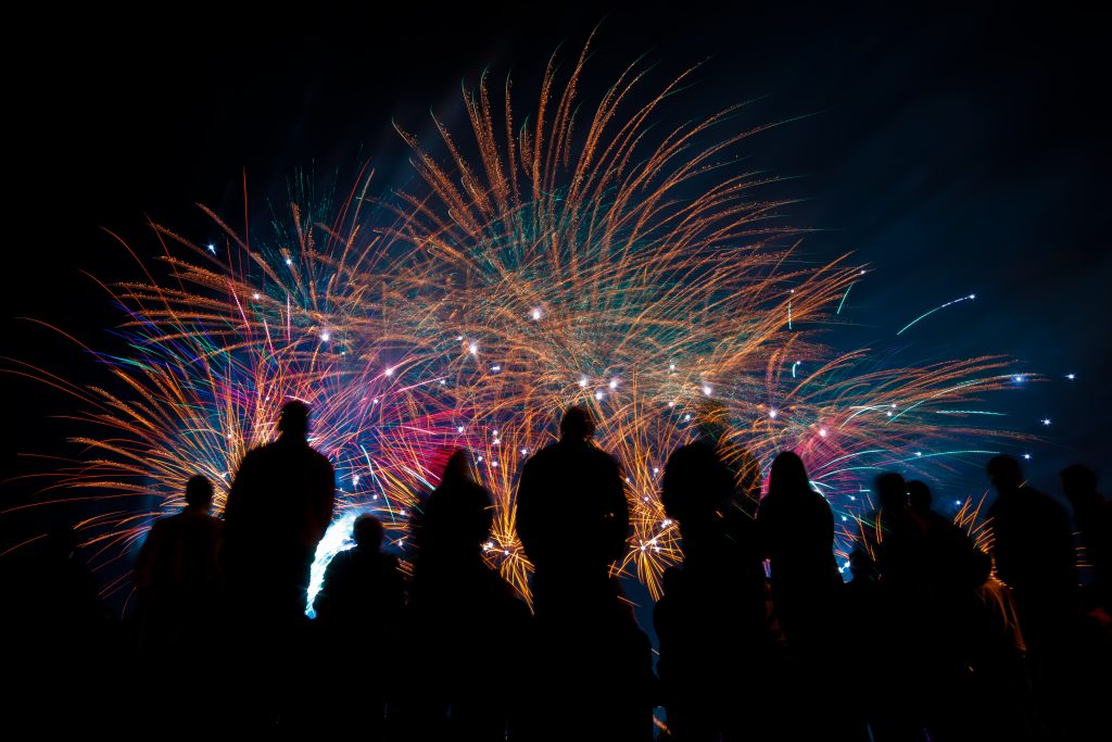 Big fireworks with silhouetted people in the foreground watching